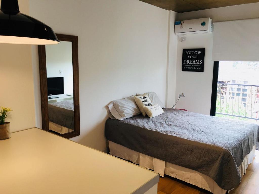 1 dormitorio con cama y espejo grande en Studio en Belén de Escobar