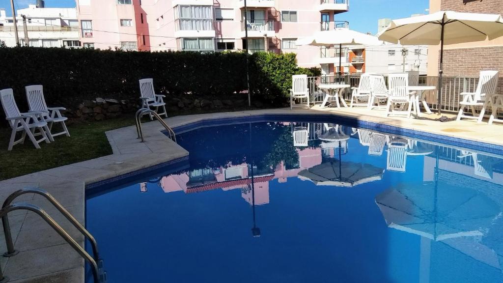 una piscina con sillas blancas y un edificio en Edificio Club del Mar, en Punta del Este