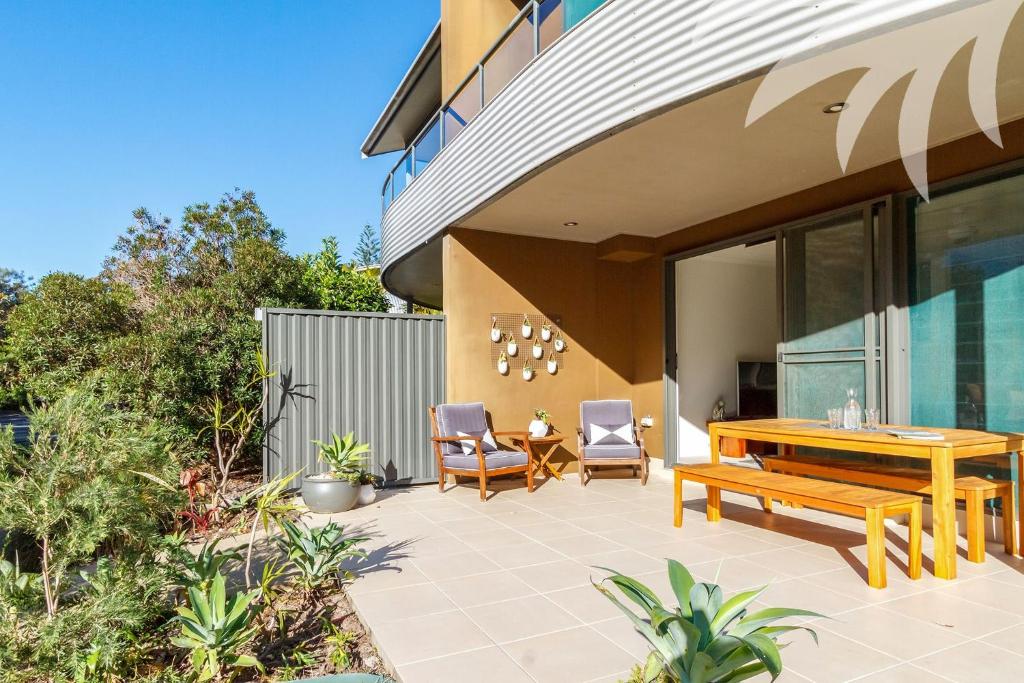 a patio with a wooden table and chairs at Boom 8 Boomerang Beach in Blueys Beach