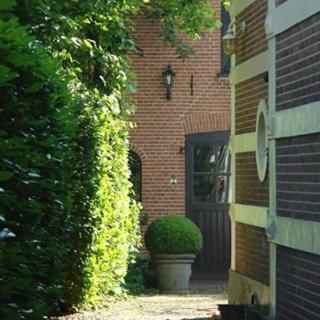 a brick house with a door and a plant at In het koetshuis in Apeldoorn