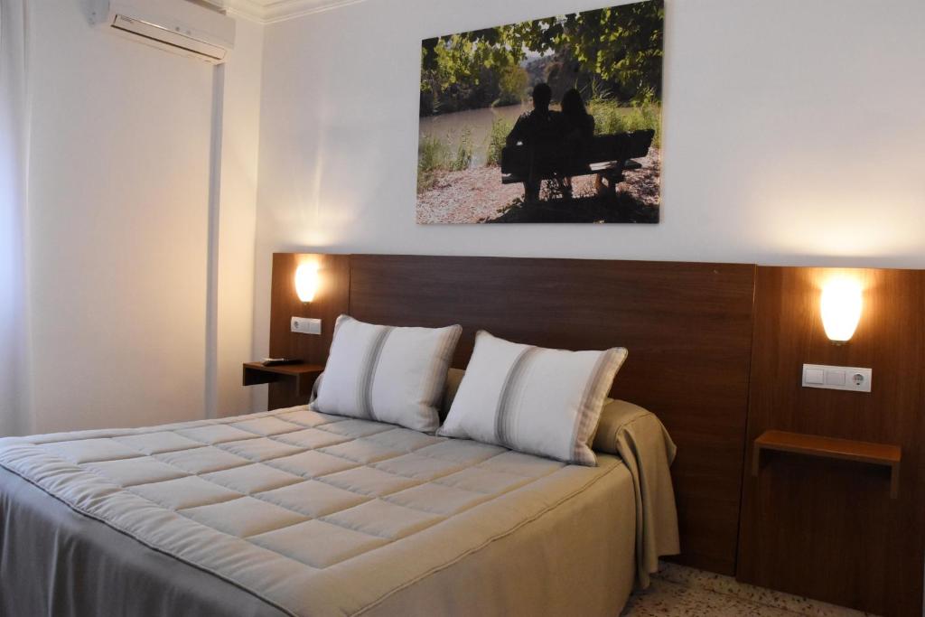 a bedroom with a bed and a painting on the wall at Hostal Restaurante El Cruce in Ardales