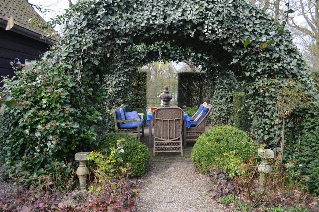 an archway with chairs and a table in a garden at The Barn in Sleeuwijk