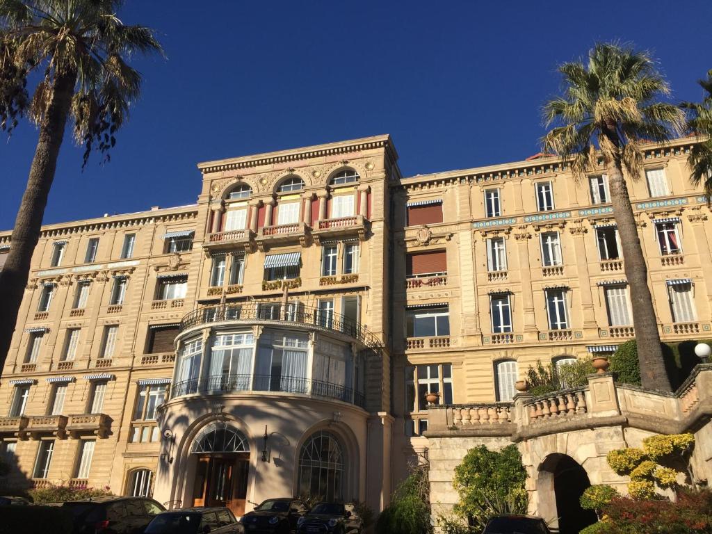 un grand bâtiment avec des palmiers devant dans l'établissement Parc CONTINENTAL, à Cannes