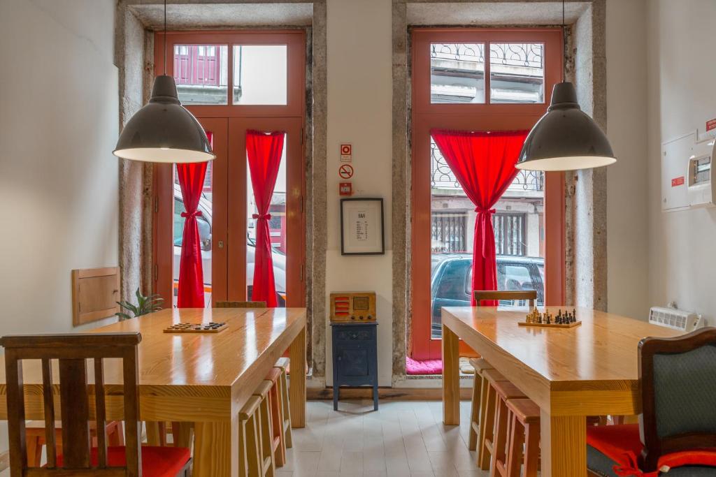 a dining room with two tables and red curtains at The Poets Inn in Porto