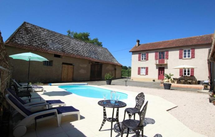 un patio con sillas, una mesa y una piscina en Maison Lajus en Bassillon-Vauzé