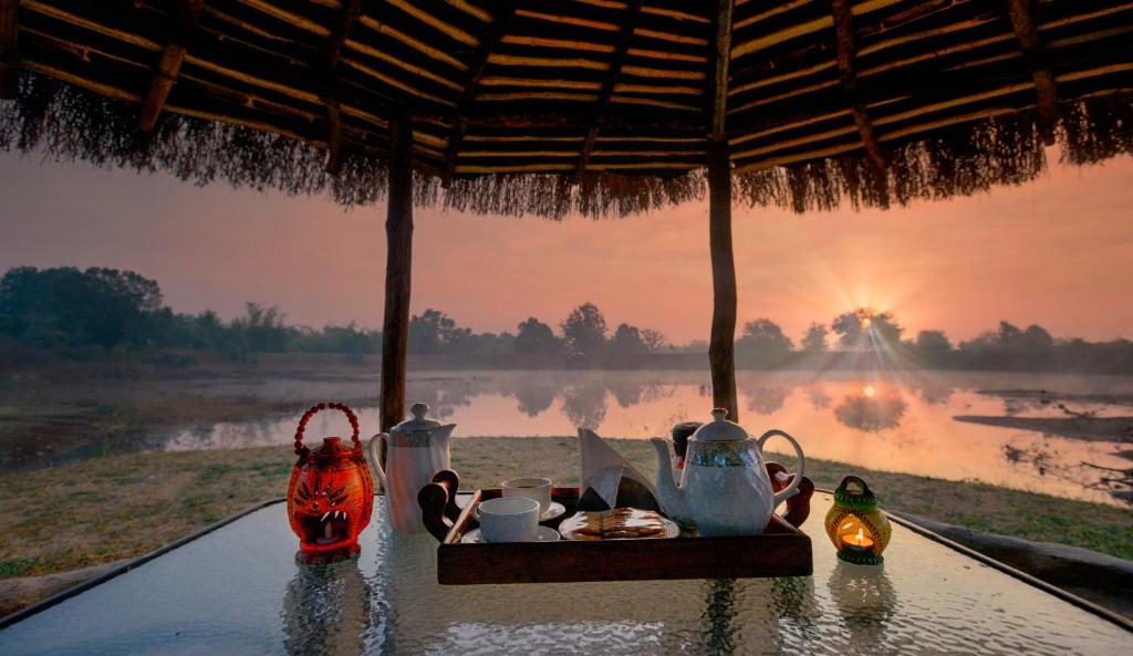 una mesa con comida y vistas al río en Pench Jungle Camp, en Khawāsa