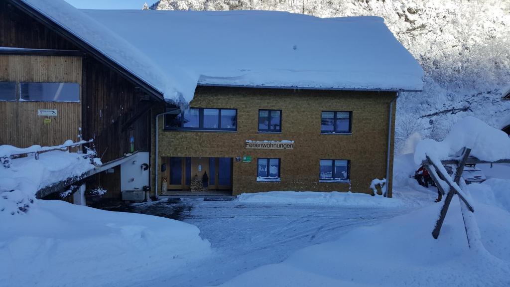 um edifício coberto de neve à sua frente em Bauernhof Dünser em Au im Bregenzerwald