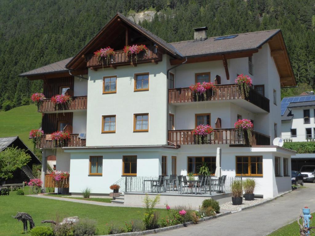 a large white house with flowers on balconies at Pension Haus Edelweiss in Weissensee