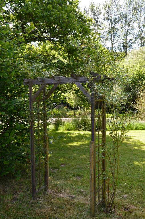 a wooden pergola in the grass in a park at Gite la Baudrière in Livaie