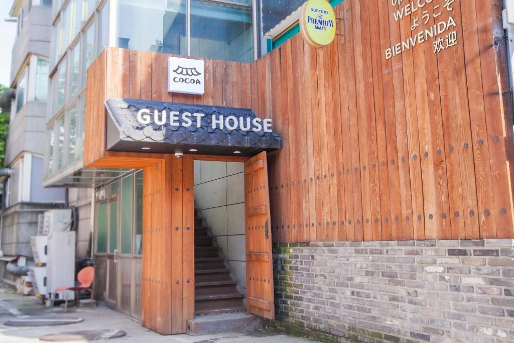 un cartel de la casa de huéspedes en el lateral de un edificio en Cocoa Guesthouse, en Seúl