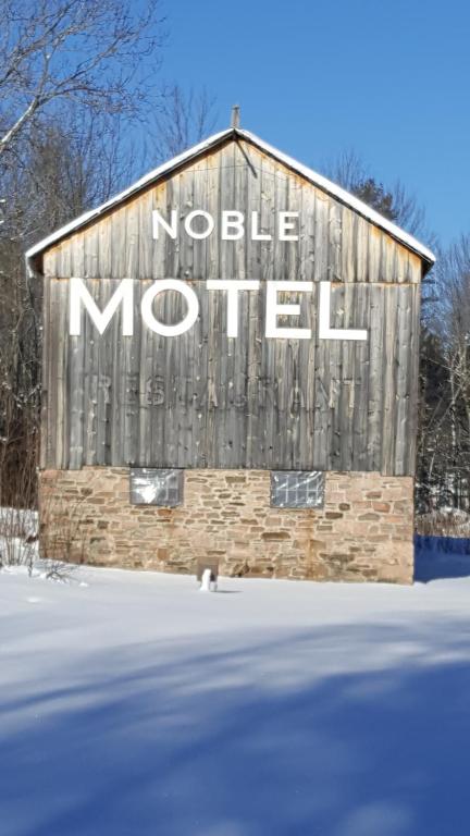 a sign on the side of a barn with the words noble morril at Noble Motel in Norland