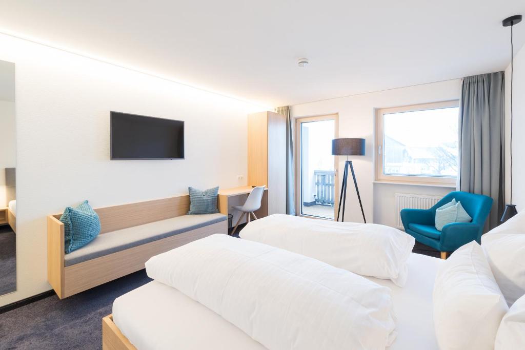 um quarto de hotel com duas camas e uma televisão em Pension Löwen em Andelsbuch