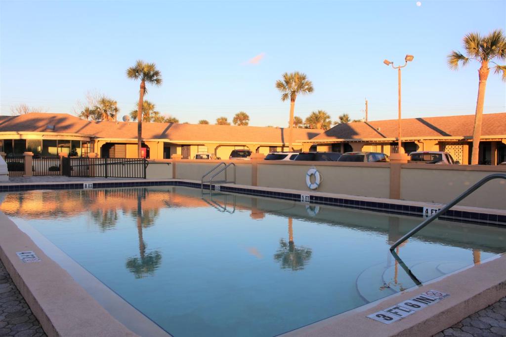 a large swimming pool with palm trees and buildings at The Lion Inn - Saint Augustine in Saint Augustine