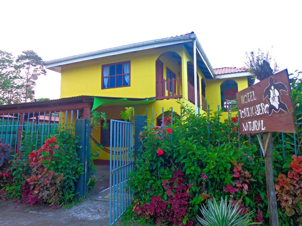 Cabinas Tortuguero Natural في تورتوجويرو: منزل اصفر وامامه لافته