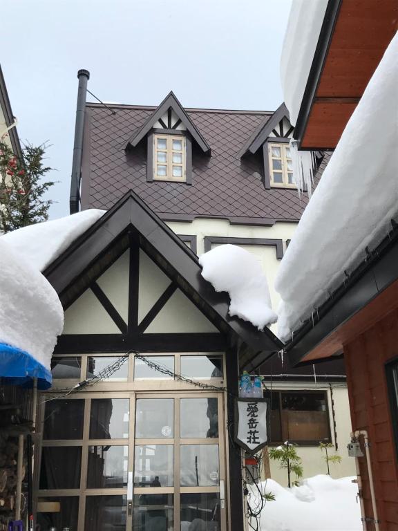 a house with snow on the roof of it at Aigakusou in Nozawa Onsen
