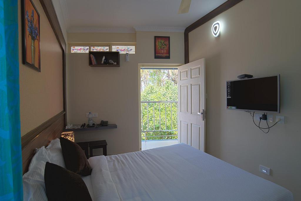 a bedroom with a bed and a tv on the wall at Gems 9 Airport Hotel in Nedumbassery