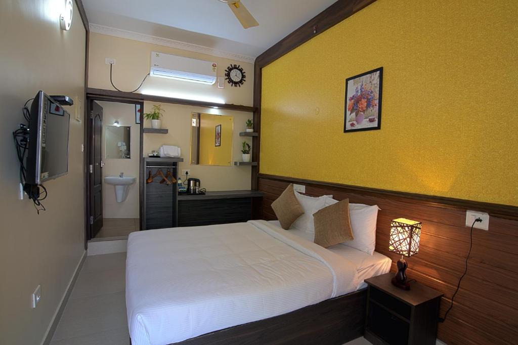 a bedroom with a white bed and a yellow wall at Gems 9 Airport Hotel in Nedumbassery