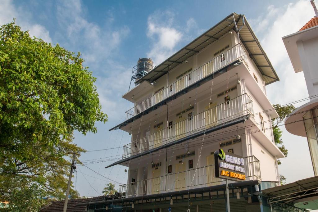a tall white building with a sign in front of it at Gems 9 Airport Hotel in Nedumbassery