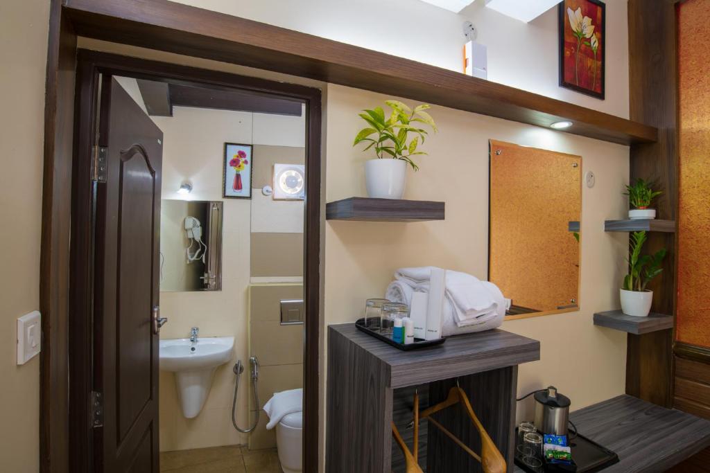 a bathroom with a sink and a toilet and a mirror at Gems 9 Airport Hotel in Nedumbassery