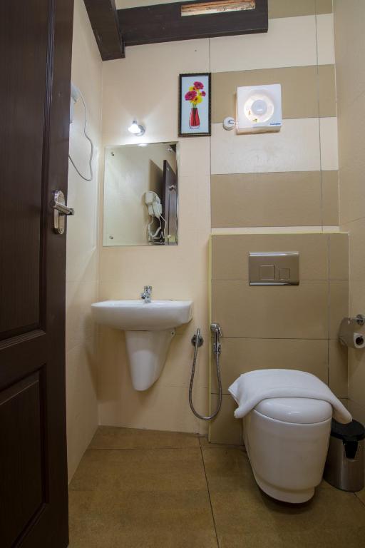 a bathroom with a toilet and a sink at Gems 9 Airport Hotel in Nedumbassery
