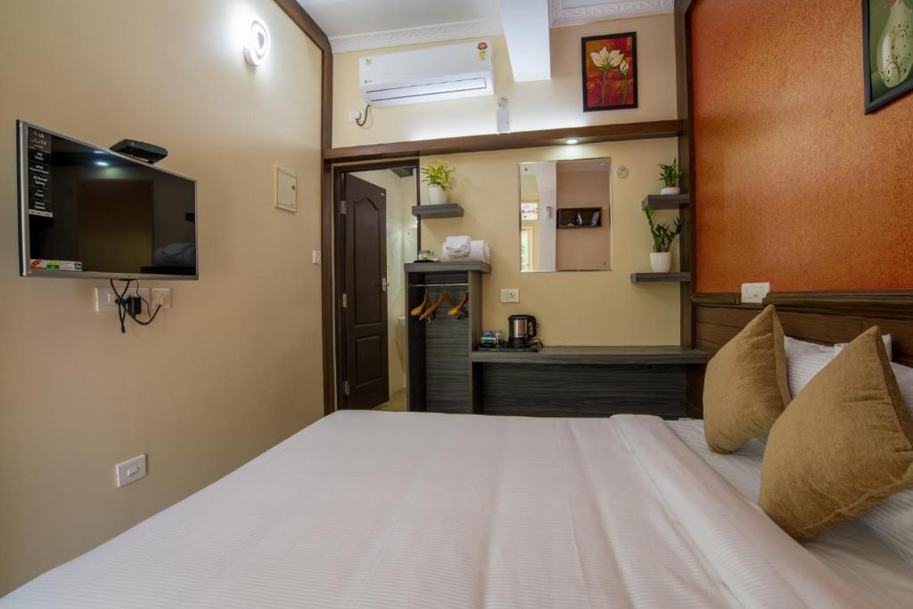a bedroom with a large bed with a tv on the wall at Gems 9 Airport Hotel in Nedumbassery
