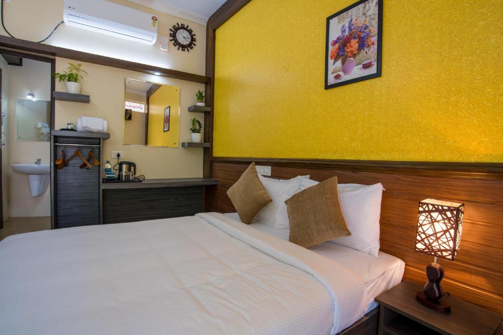 a bedroom with a white bed and a yellow wall at Gems 9 Airport Hotel in Nedumbassery
