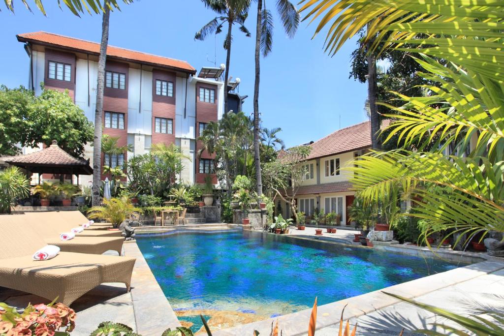 uma piscina em frente a um edifício com palmeiras em Restu Bali Hotel em Legian