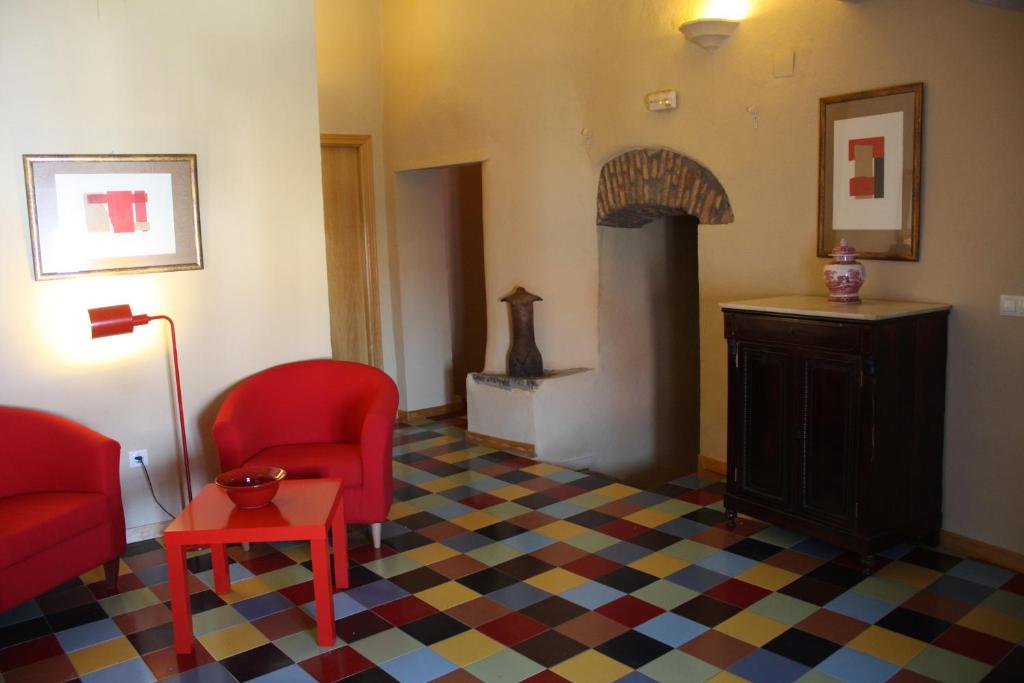een woonkamer met 2 rode stoelen en een open haard bij La Cantarera in Herguijuela