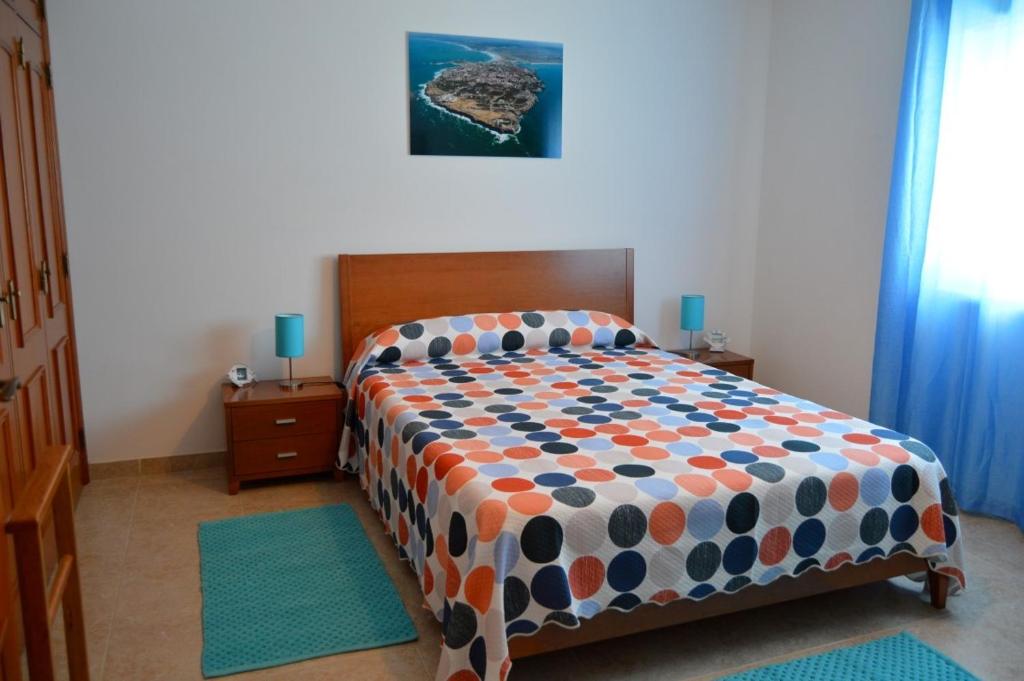 um quarto com uma cama com um edredão colorido em Apartamento na Cidade do Surf em Peniche