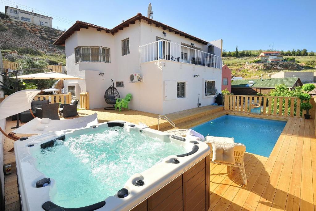 a hot tub on a patio with a house at Family Villa in Safed