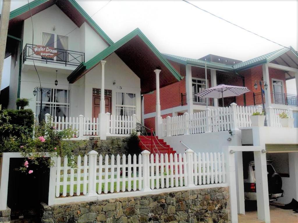 a white picket fence in front of a house at Winter Dream Holiday Bungalow Nuwara Eliya in Nuwara Eliya