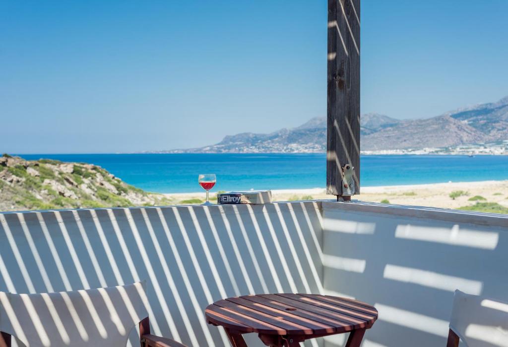 a glass of wine sitting on top of a balcony with the ocean at Athena Villas in Makry Gialos