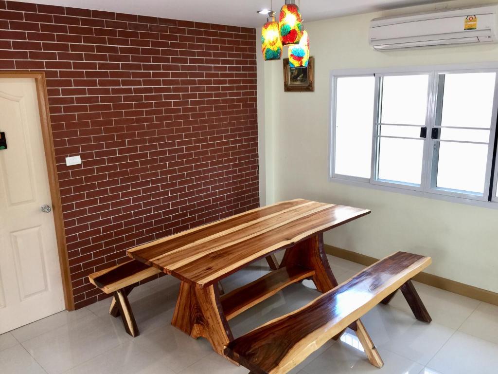 a wooden table and bench in a room with a brick wall at Oriental Beach By Winnie in Cha Am