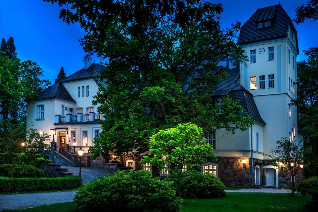 een groot wit huis met 's nachts een toren bij Pałac Ciekocinko Hotel Resort & Wellness in Ciekocinko