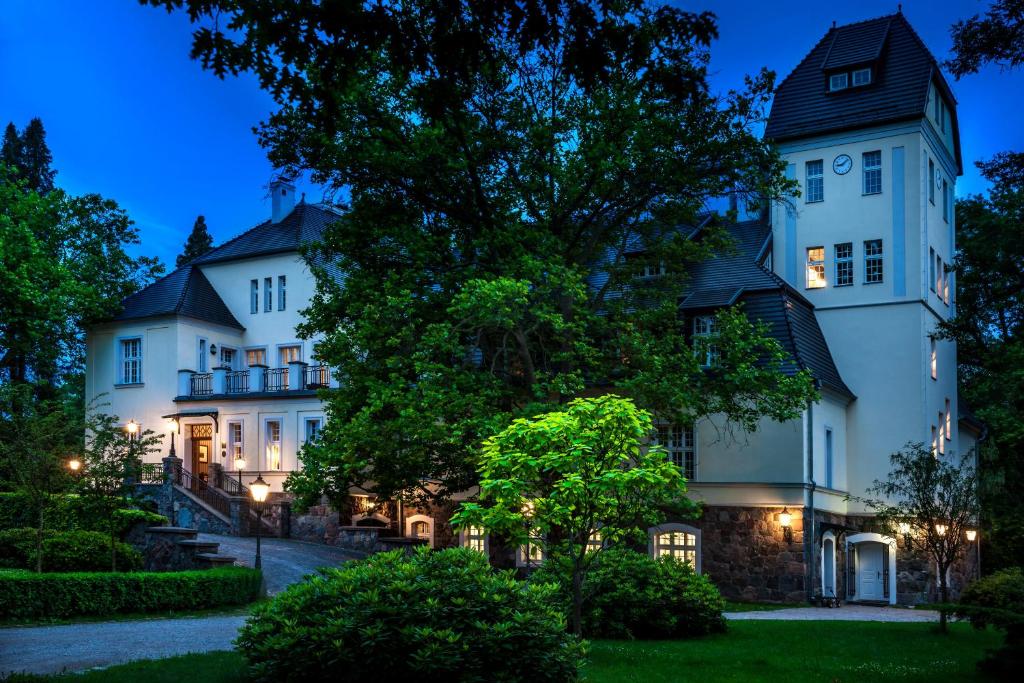 una gran casa blanca con una torre por la noche en Pałac Ciekocinko Hotel Resort & Wellness, en Ciekocinko