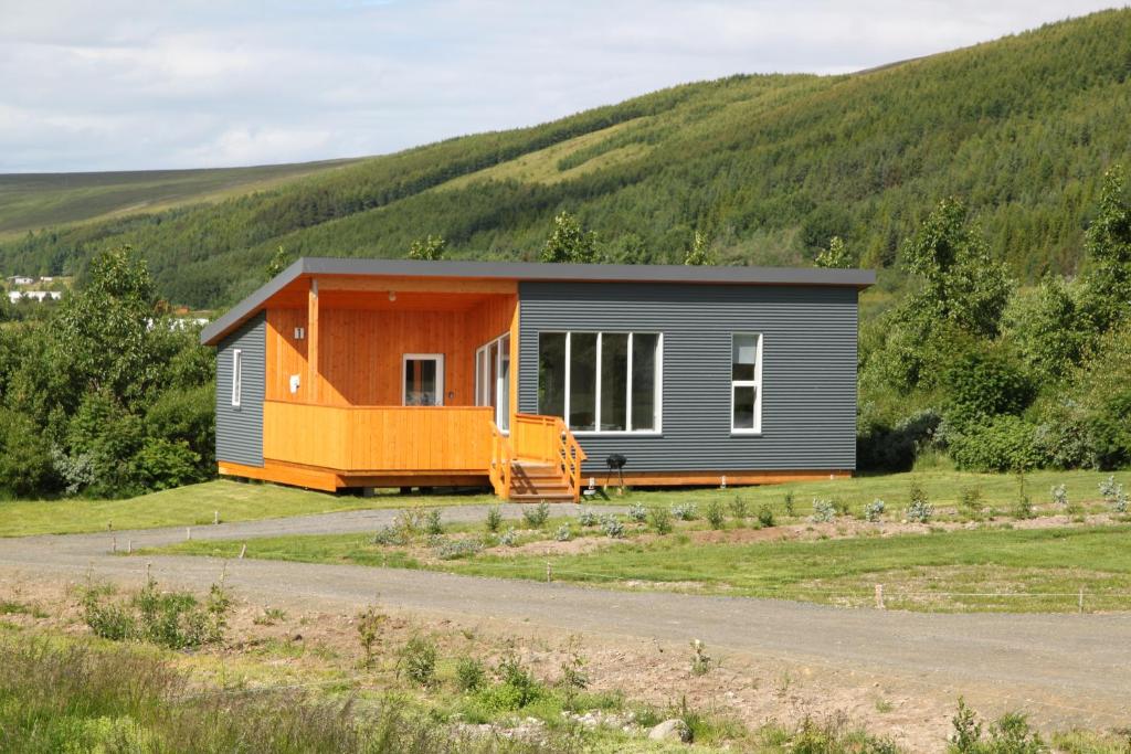 an orange and gray house on the side of a road at Kjarnagerdi Cottages in Laugar