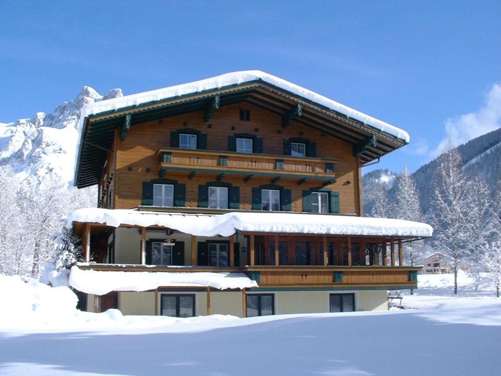 un grand bâtiment en bois avec de la neige au-dessus dans l'établissement Haus Alpina, à Werfenweng