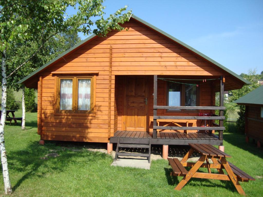 a small wooden cabin with a porch and a deck at Domki "Na Dworskiej" Polańczyk 696-025-331 in Polańczyk