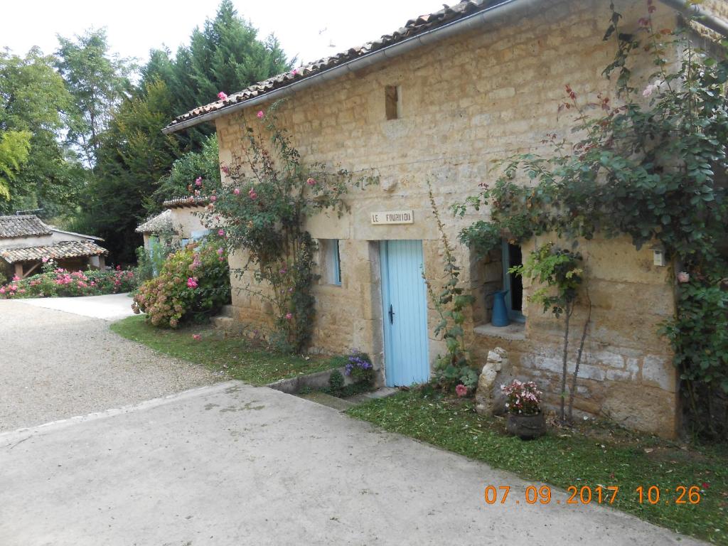 ein Steinhaus mit blauer Tür und Blumen in der Unterkunft Chambre d'hotes Le Fourniou in Melle