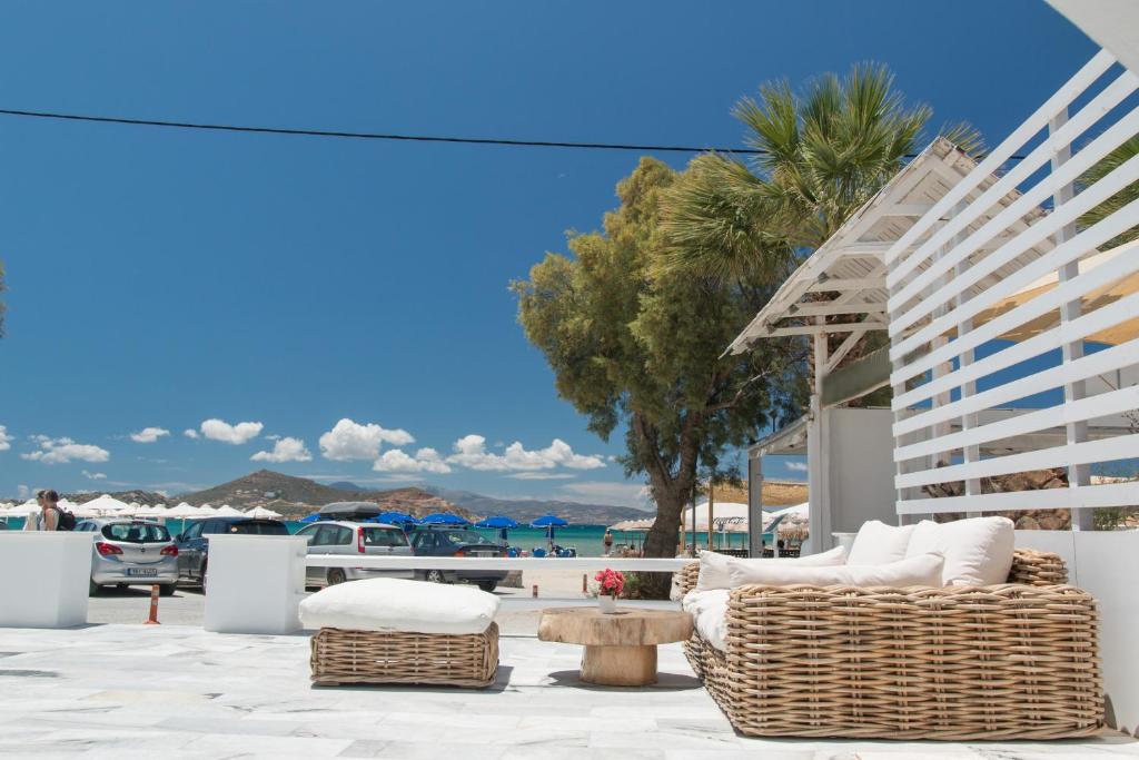 um pátio com cadeiras de vime, uma mesa e palmeiras em Ippokampos Beachfront em Naxos Chora