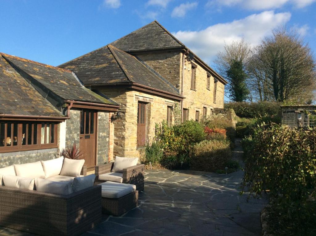 a stone house with a patio with a couch at Owletts Barn B&B in Bodmin