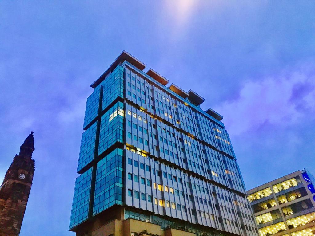 グラスゴーにあるGlasgow Central Station SKYLINE Apartment with Parking (2 bedrooms, 2 bathrooms, 1 living room-Kitchen)の時計塔のある高い青いガラスの建物