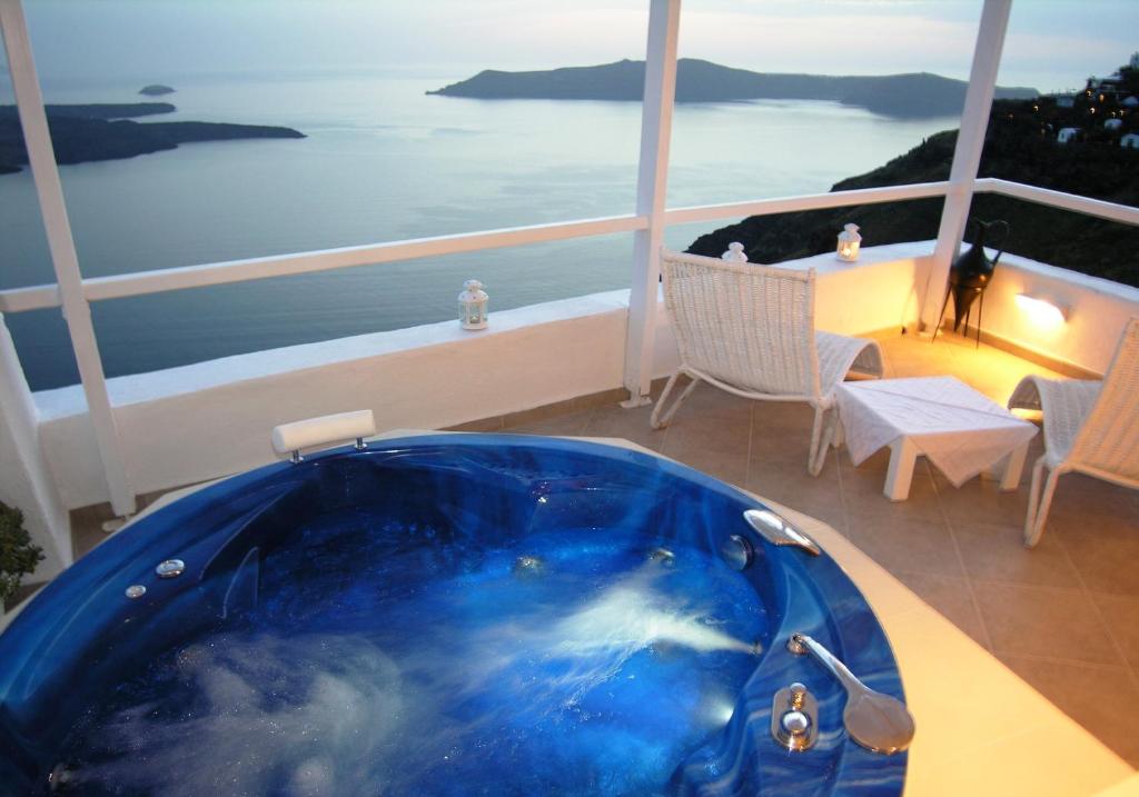 a blue bath tub on a balcony with a view of the ocean at Aeolos Art & Eco Suites Adults Only in Imerovigli
