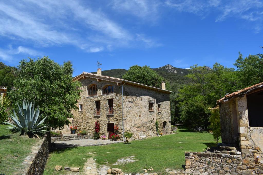 ein altes Steingebäude auf einem Grasfeld in der Unterkunft Can Pedragos in Sales del Llierca