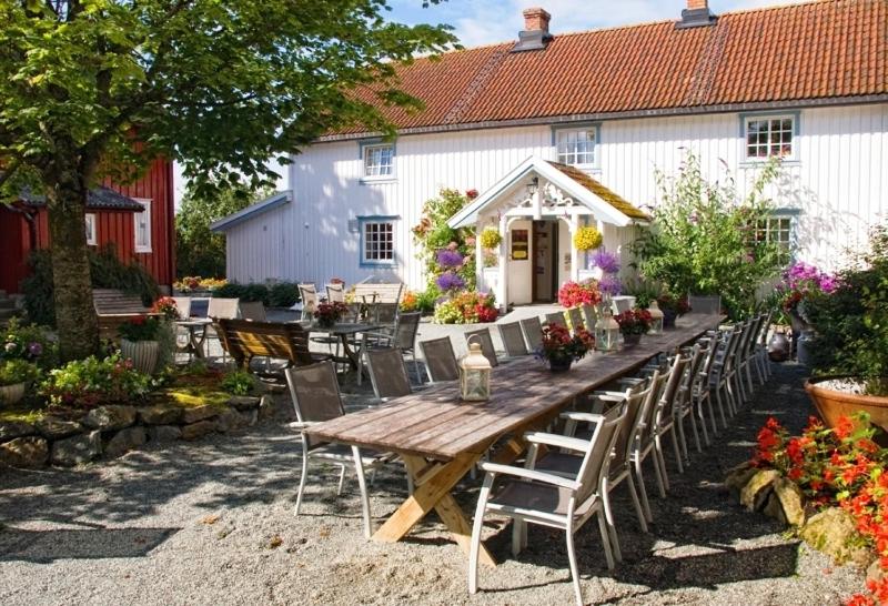 un tavolo in legno con sedie di fronte a un edificio bianco di Klostergården Bed & Breakfast a Tautra