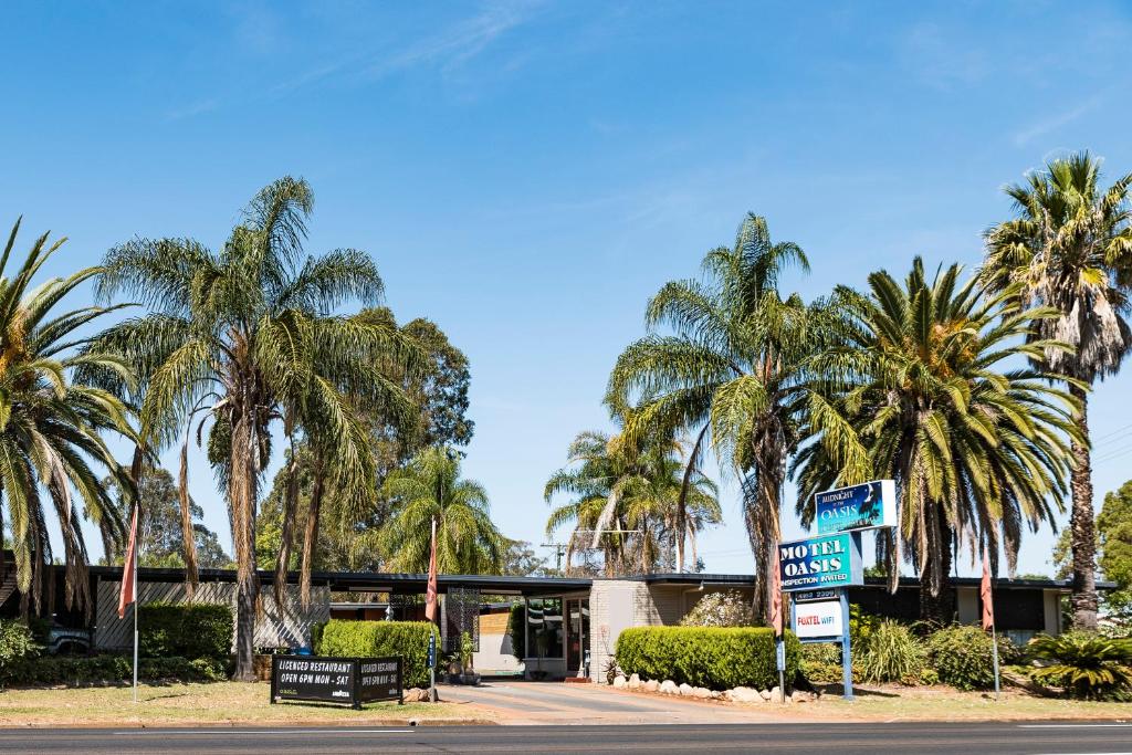 un letrero de la calle frente a un edificio con palmeras en Motel Oasis, en Kingaroy