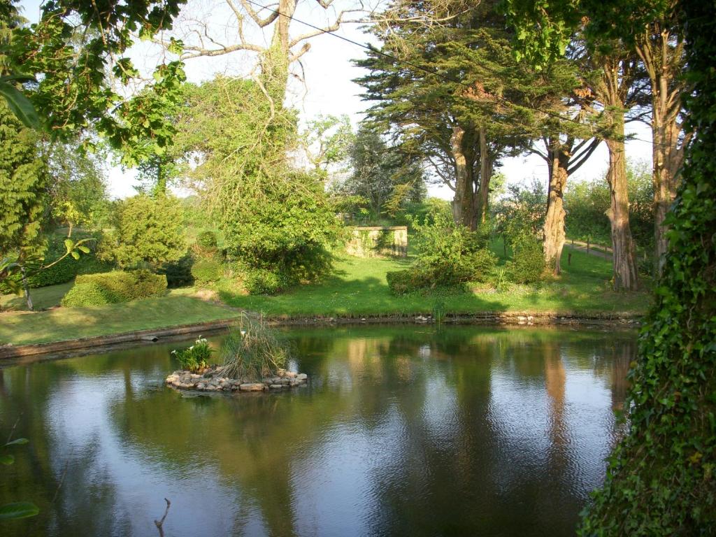 um lago no meio de um parque com árvores em Les Peupliers em Vesly