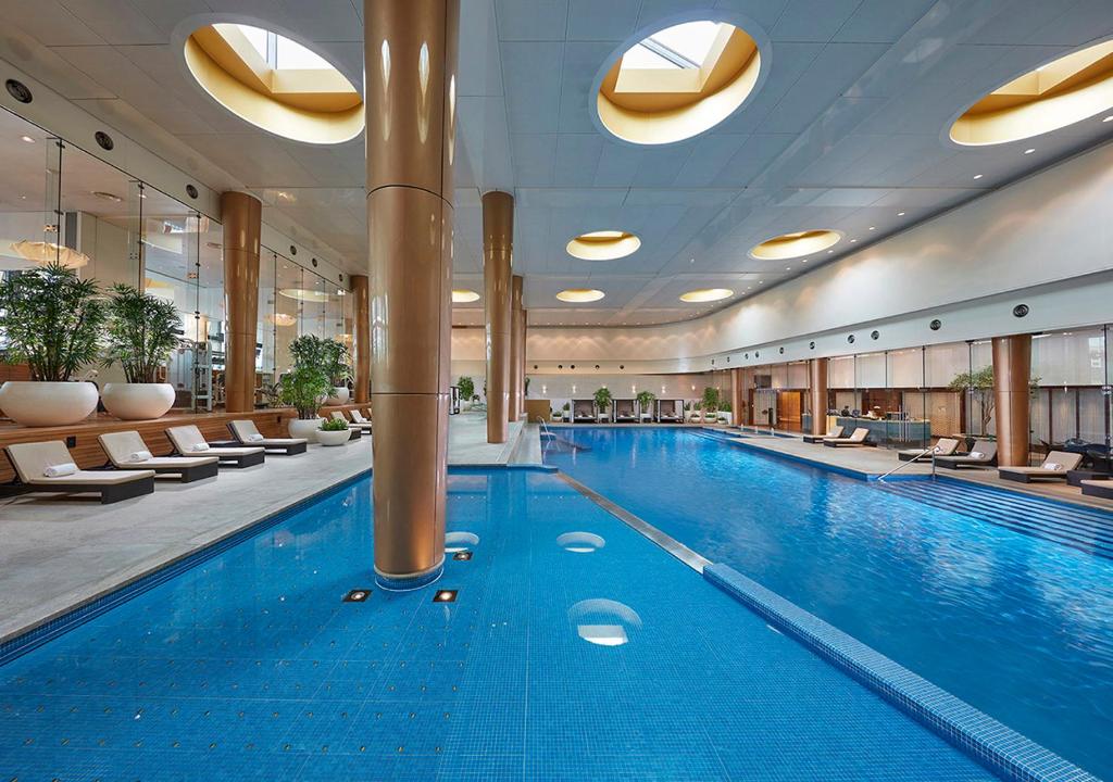 a large swimming pool in a hotel with chairs at Crown Towers Melbourne in Melbourne