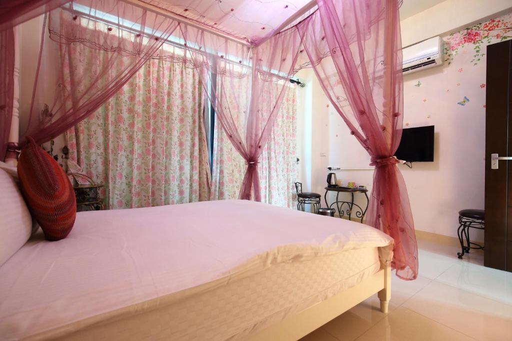 a bedroom with a canopy bed with pink drapes at Dear B&amp;B in Hualien City