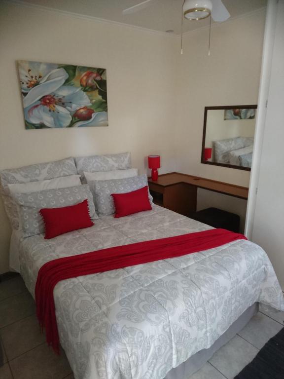 a bedroom with a large bed with red pillows at Chanelle Self Catering in Bloemfontein